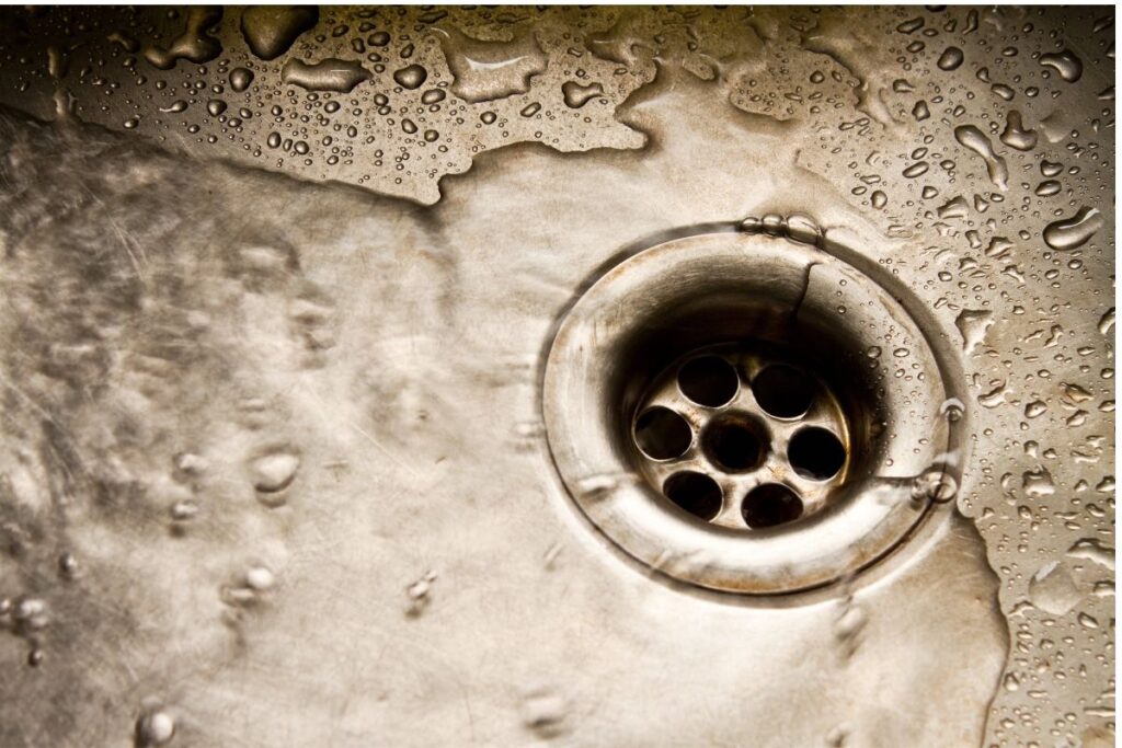 Water flows down a drain. Act now to prevent slow drains.