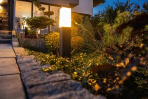 The focus is on the outdoor lighting next to a home path. The light is surrounded by greenery.